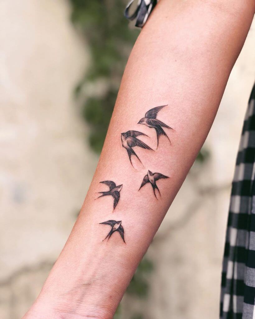 Black female tattoo of birds on the forearm