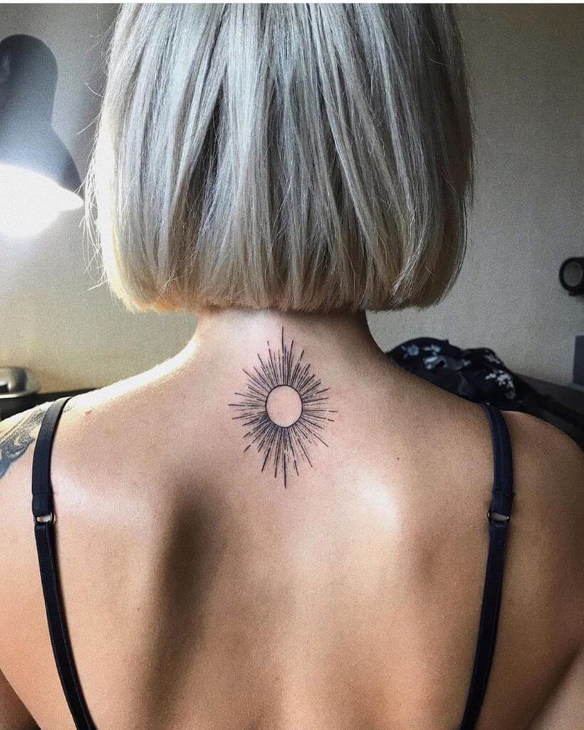 Black tattoo of a sun on the back of the neck