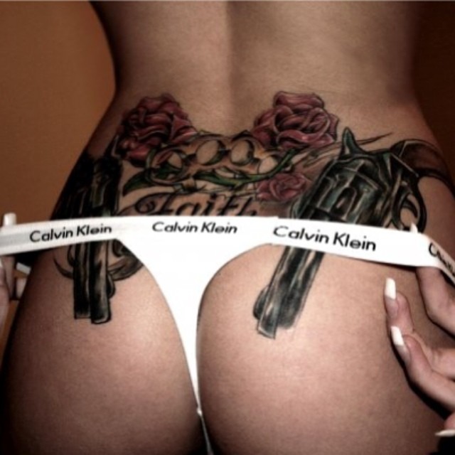 Womans lower back tattoo of guns and roses