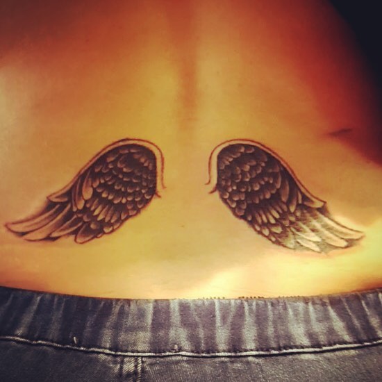 Wings tattoo on the womans lower back