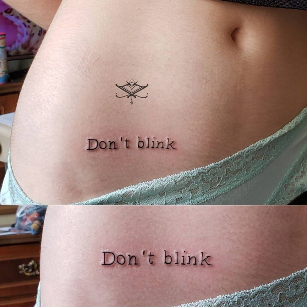Lettering black tattoo for women of "Don't blink" written on the right side of belly