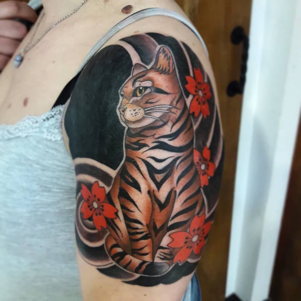 Neo traditional color tattoo for woman of a cat with red flowers on left shoulder