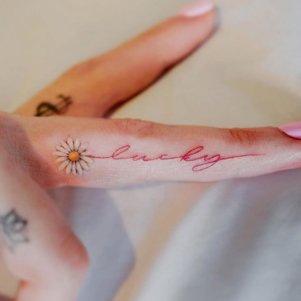 Lettering color tattoo for women with "Lucky" written on the finger