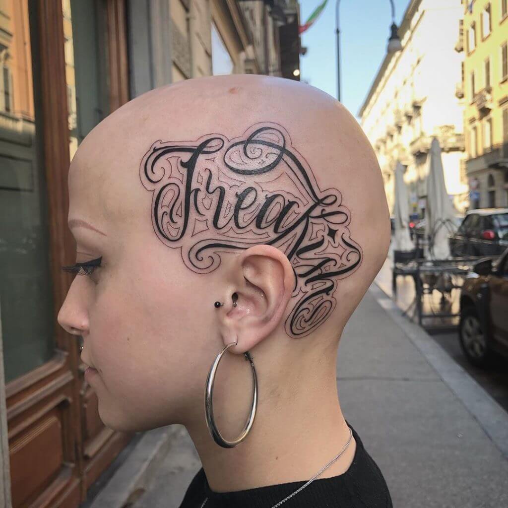 Lettering black tattoo for women of "Freakish" on the left side of the head
