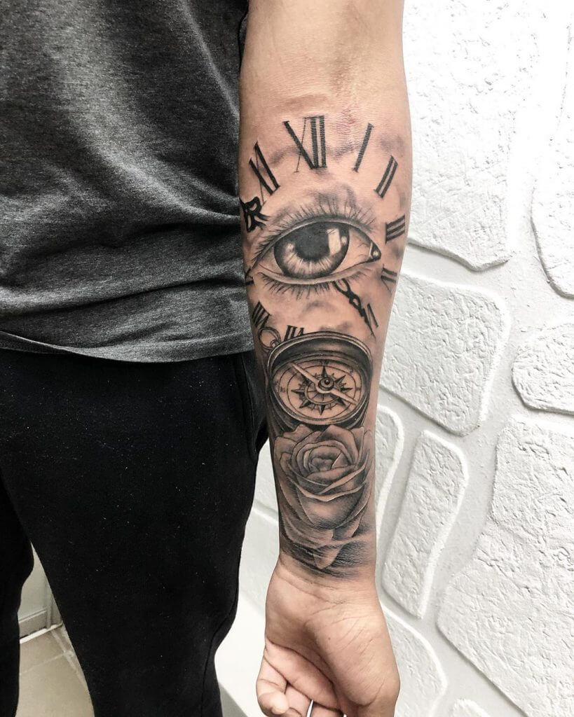 Mens neotraditional tattoo of an eye, a clock, a compass and rose on the left forearm