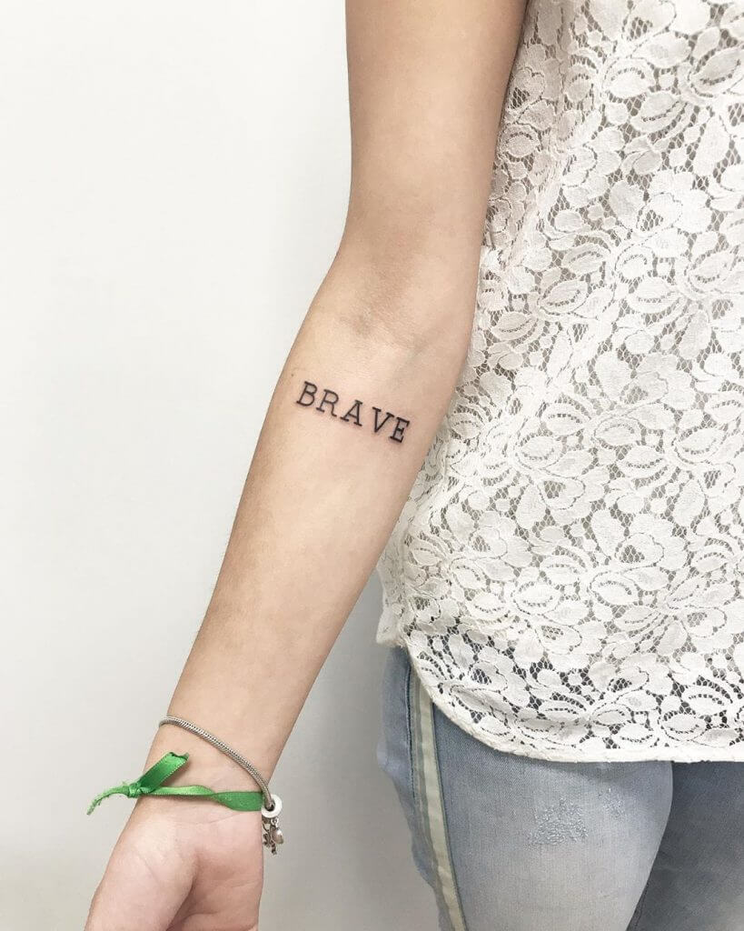 Lettering tattoo for women with "BRAVE" written on the right forearm