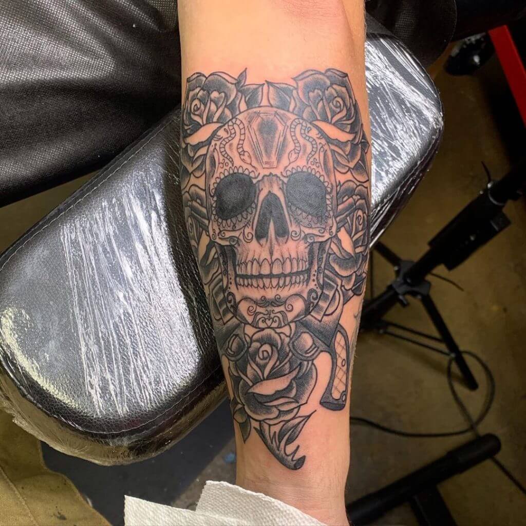 Black neotraditional tattoo with a skull and roses around on the right forearm