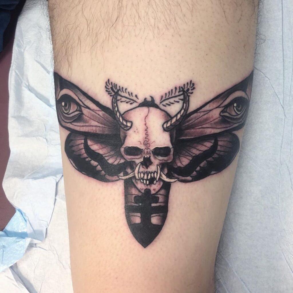 Black neotraditional tattoo with a devil skull and a butterfly