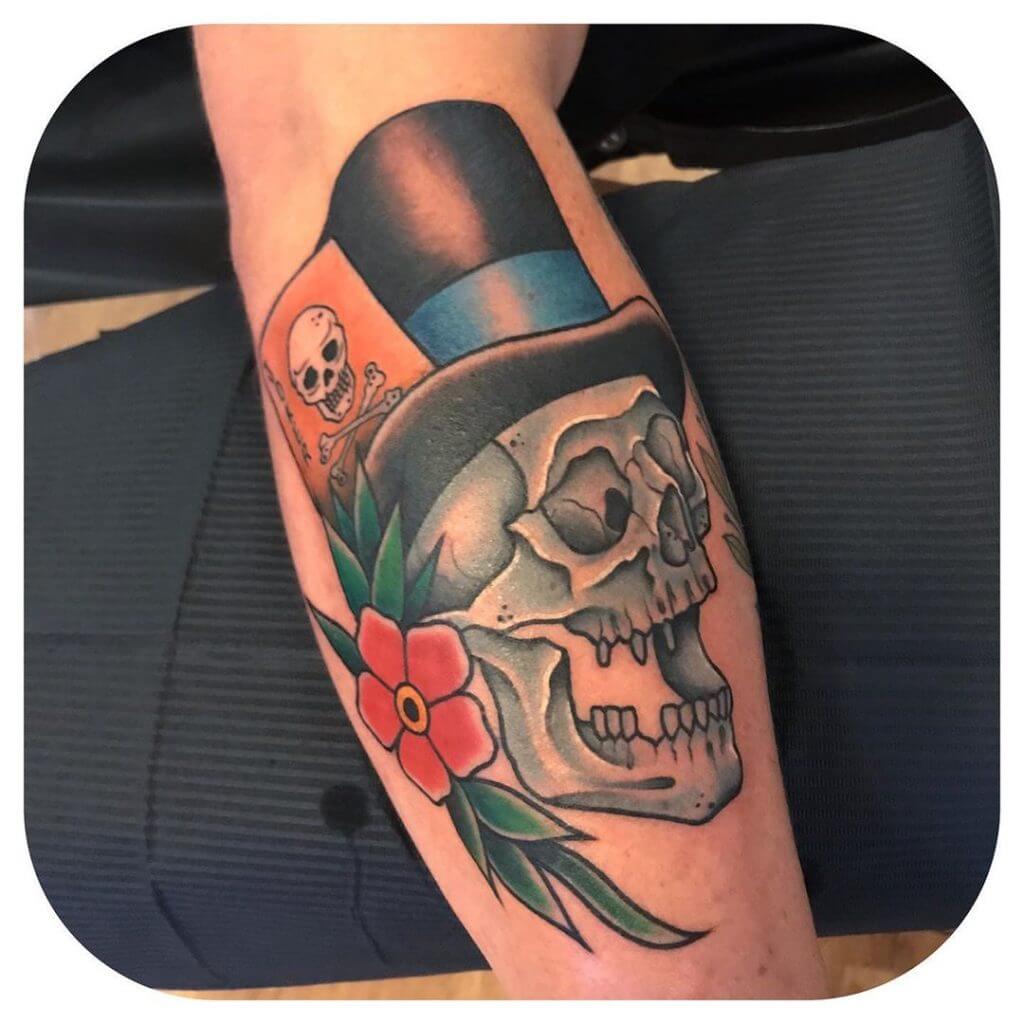 Color neo traditional tattoo of a skull with top hat and a flower on the right arm