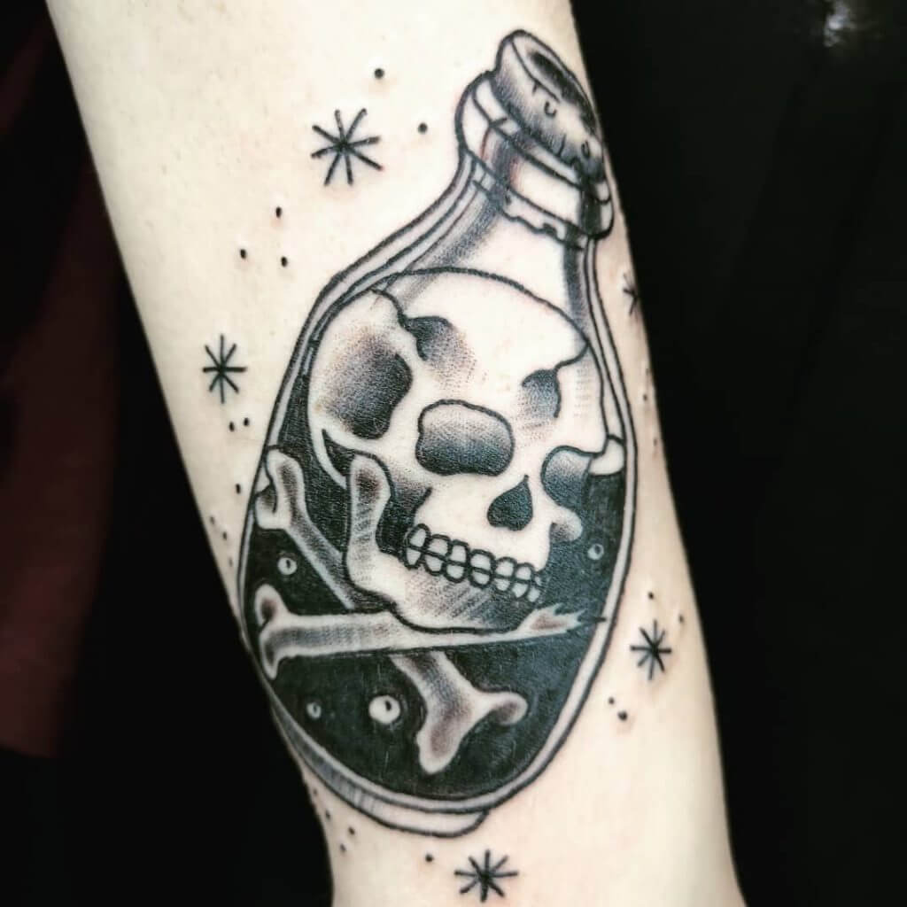 Black neotraditional tattoo with a skull and bones in the bottle on the forearm