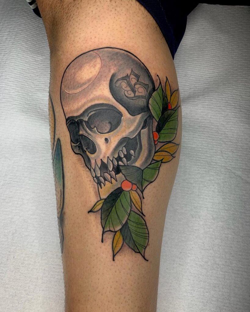 Color neotraditional tattoo of a skull and a leaves on the calf
