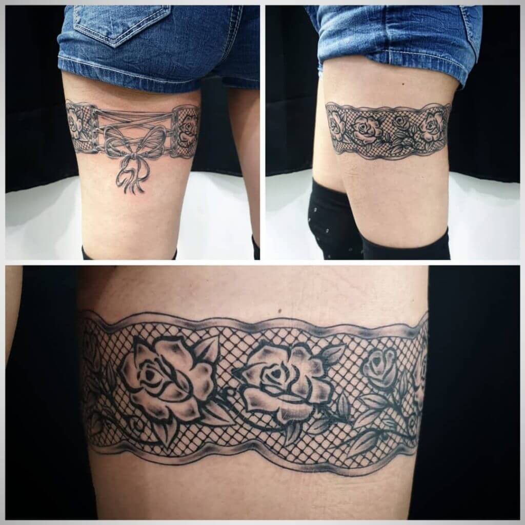 Women black and gray dotwork tattoo of a garter on the left thigh