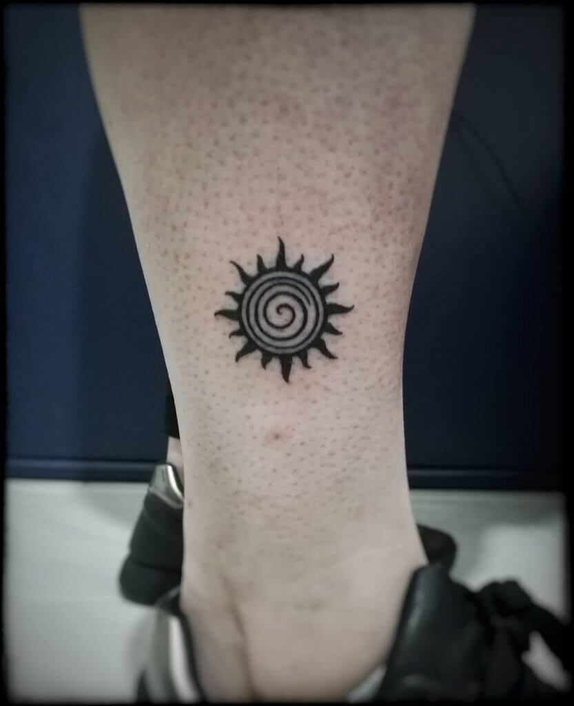 Tribal black sun tattoo above the right ankle