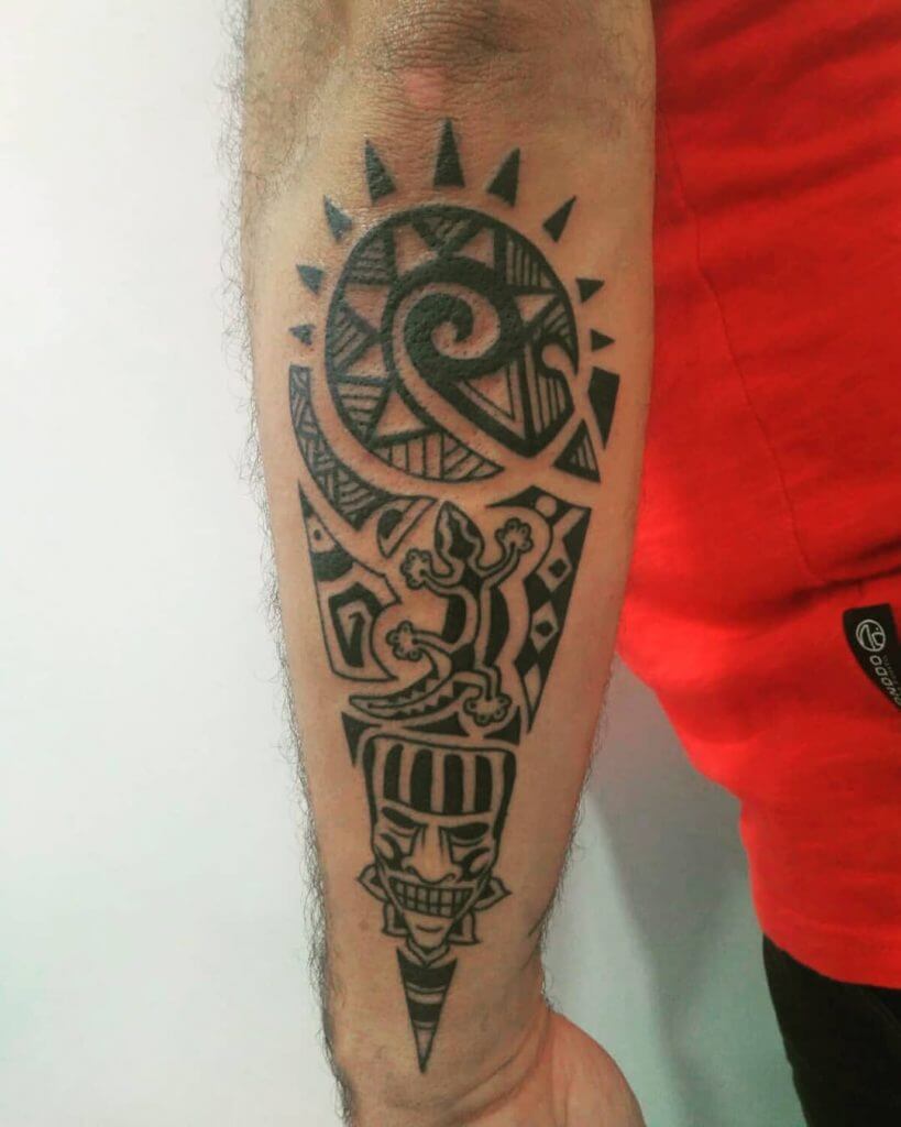 Tribal black sun tattoo on the left forearm