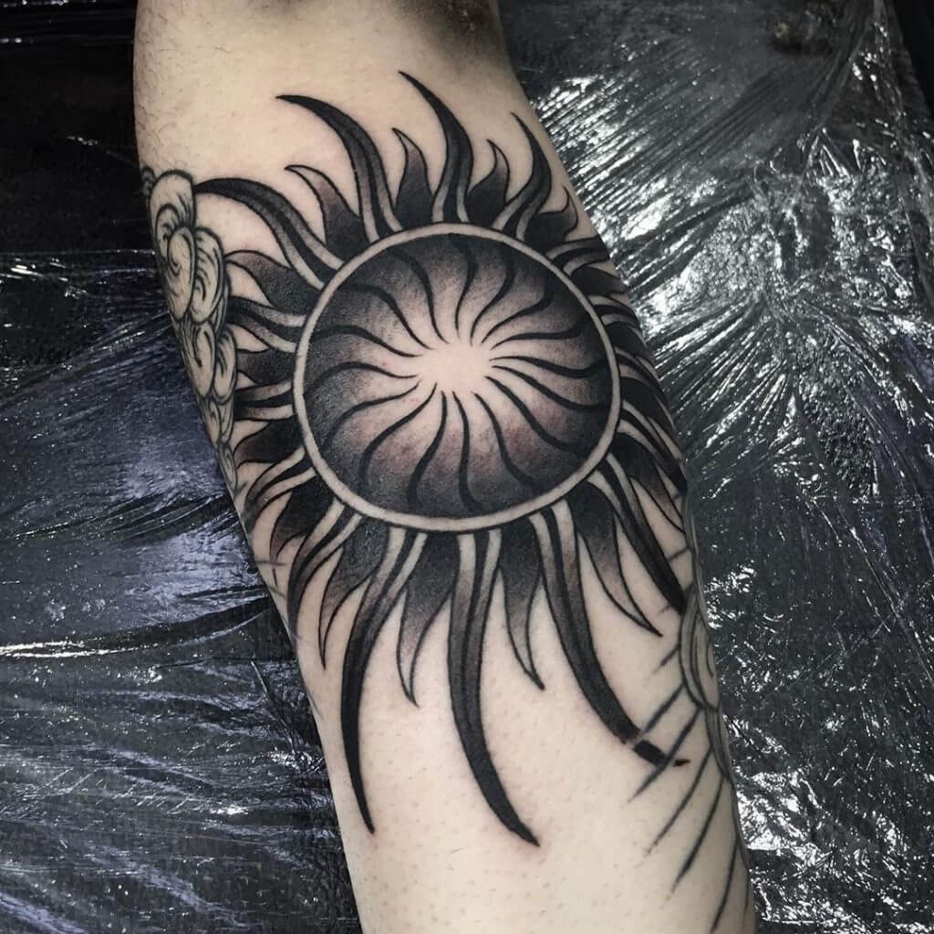 Black sun tattoo on the forearm