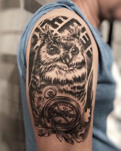 Black owl tattoo with a compass for men on the right arm