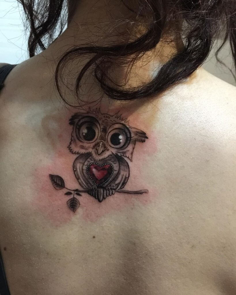Black owl tattoo with a red heart for women on the back