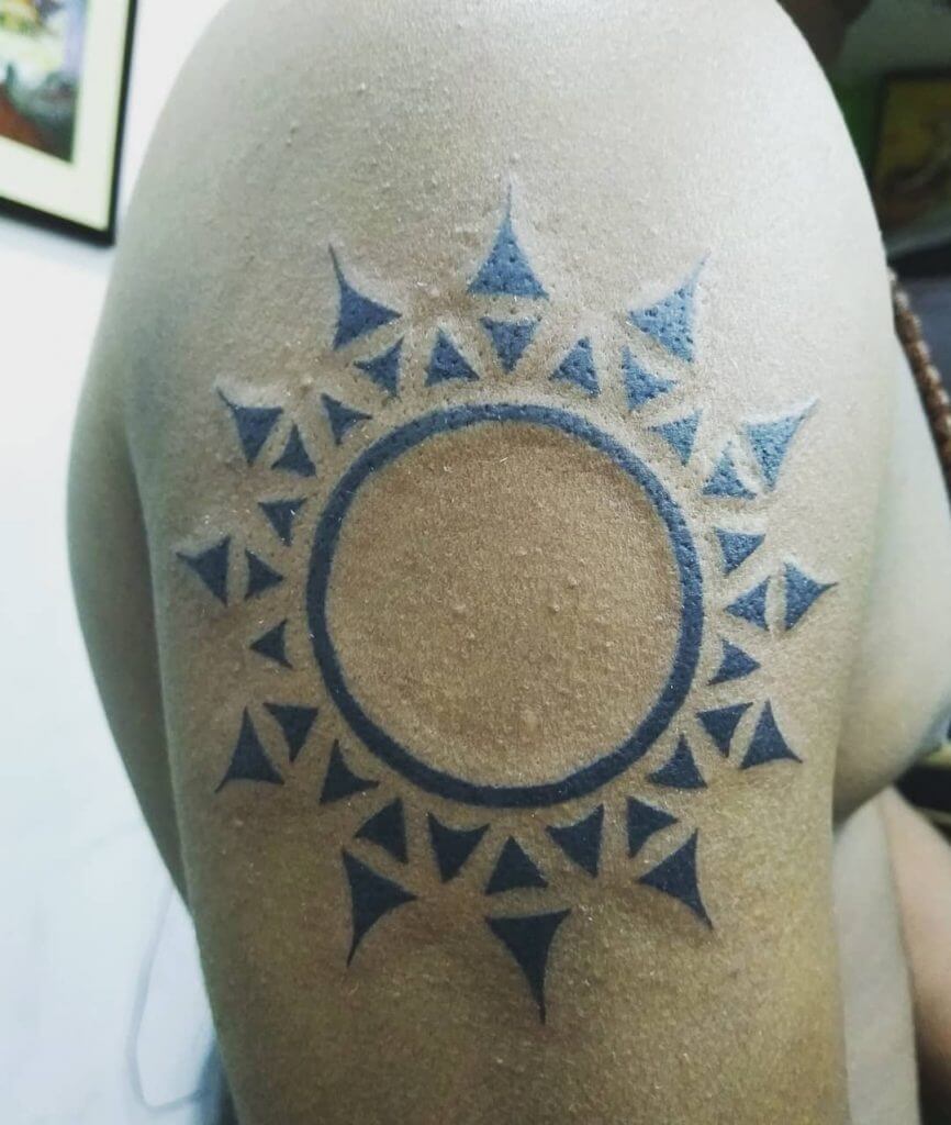 Tribal black sun tattoo on the right arm
