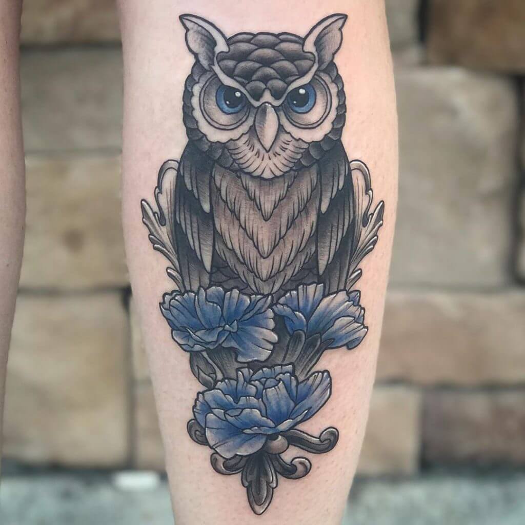 Black owl tattoo with blue flower for women on the right calf