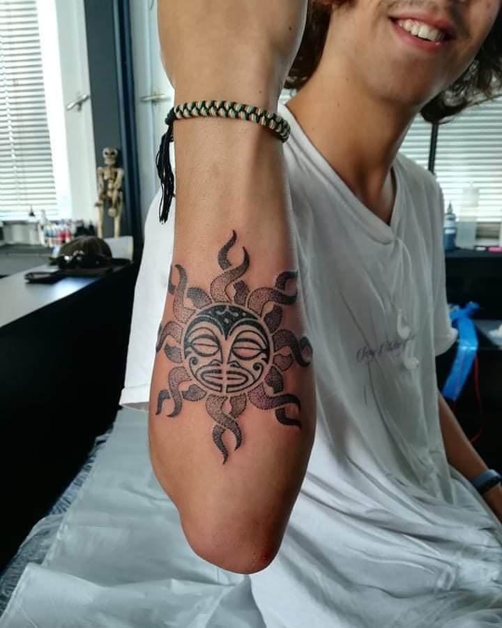 Tribal black sun tattoo on the right forearm
