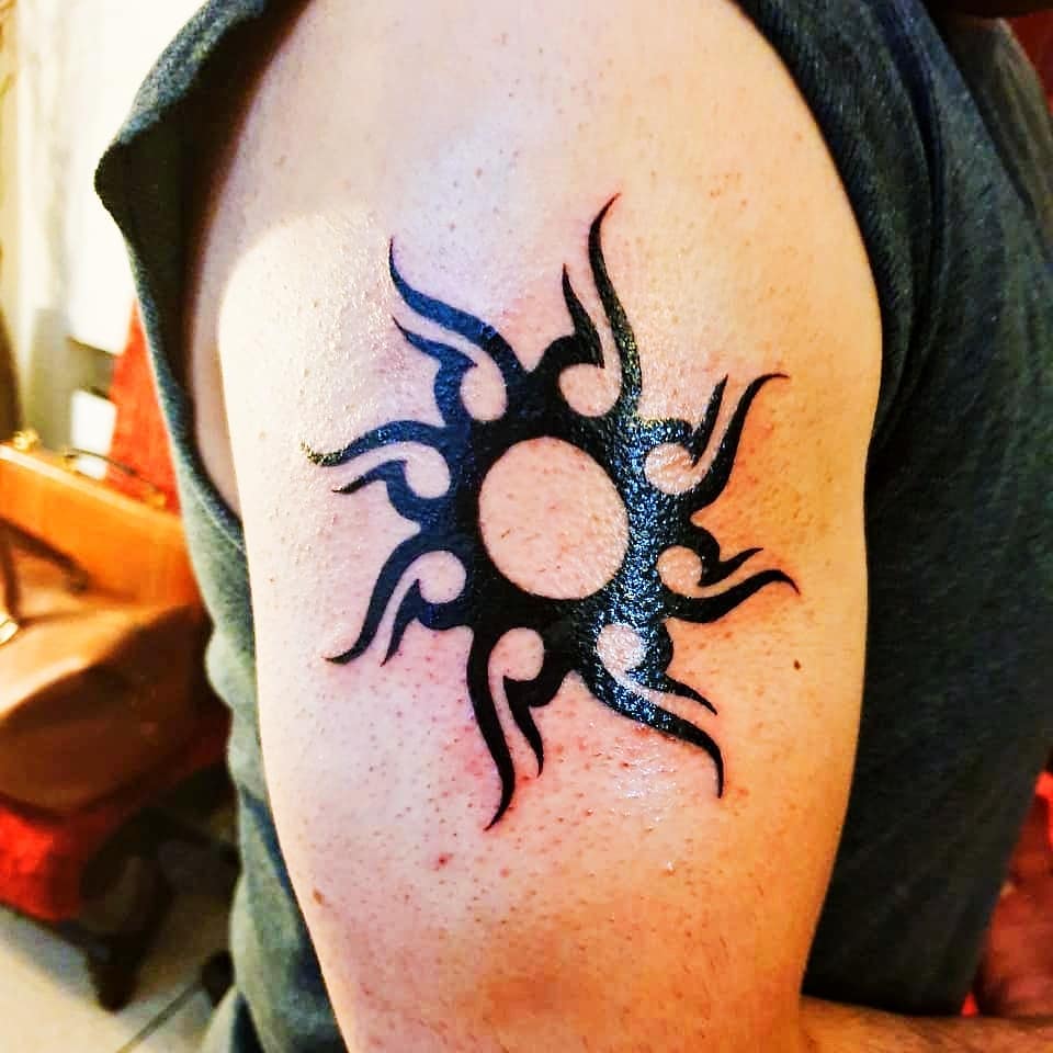 Tribal black sun tattoo on the right arm