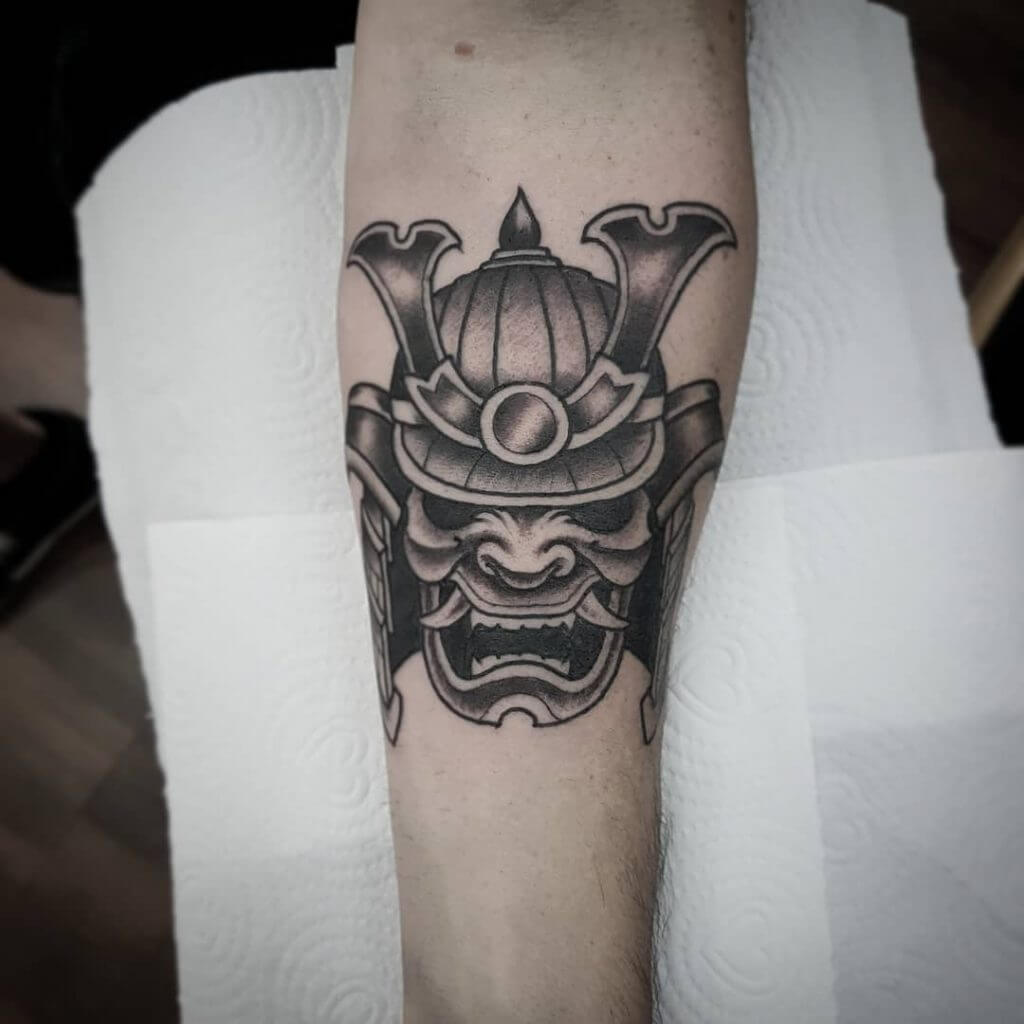 Black samurai mask tattoo on the forearm