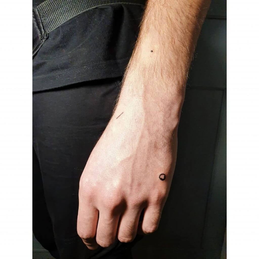 Small black abstract tattoo on the left forearm