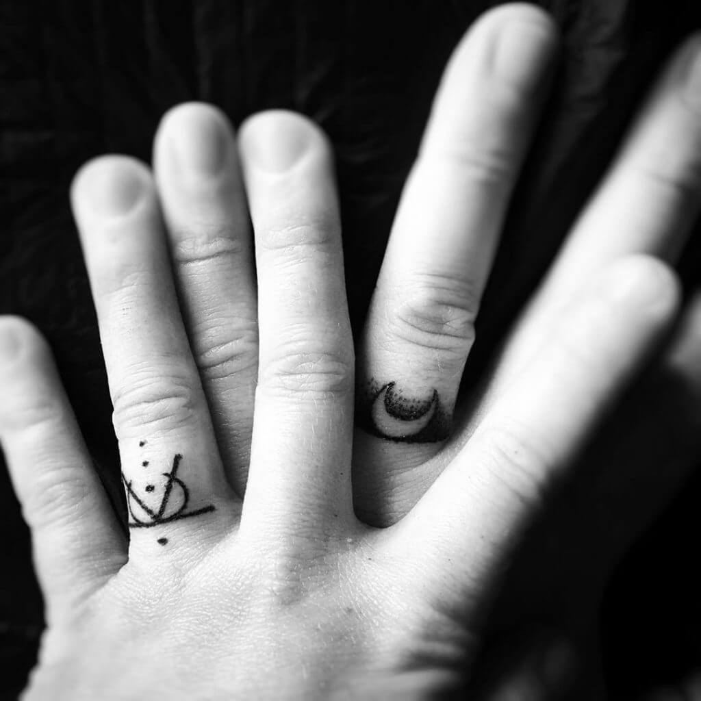 Small black abstract tattoo on the fingers