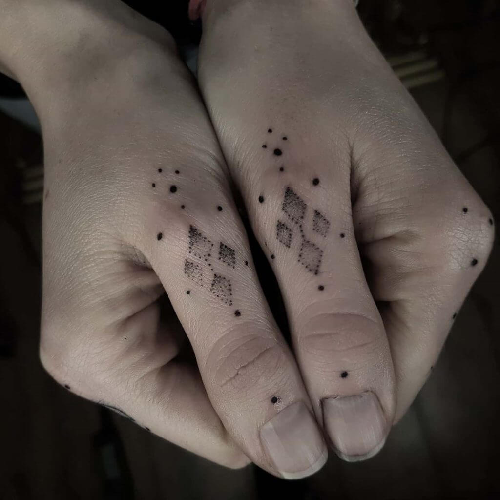 Small black abstract tattoo on the fingers