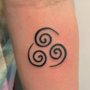 Small black abstract tattoo on the left forearm