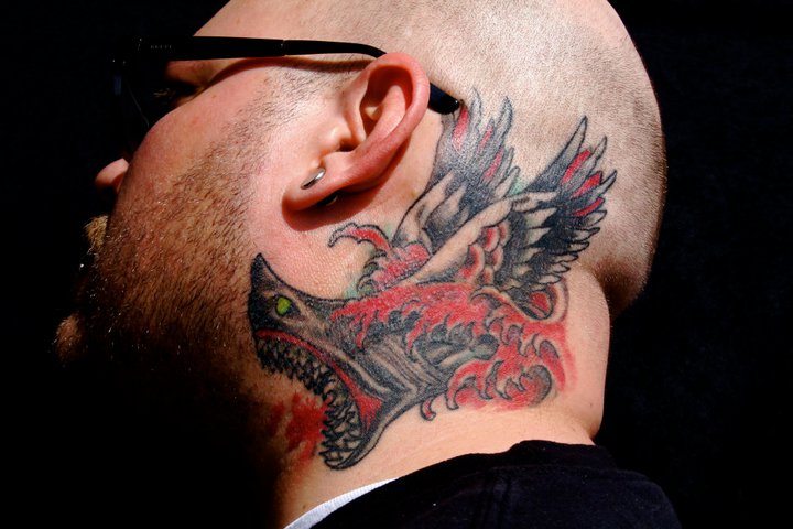 Neck shark tattoo with an open mouth and wings