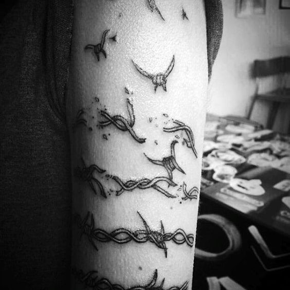 Broken barbwire arm tattoo artwork capturing the essence of freedom and confinement.