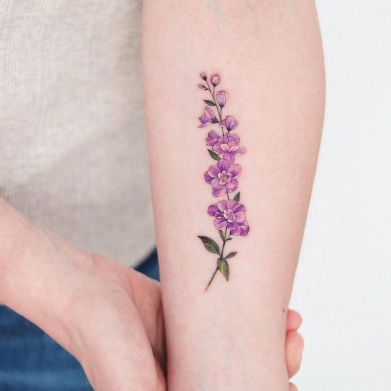 Pink larkspur flower tattoo on forearm