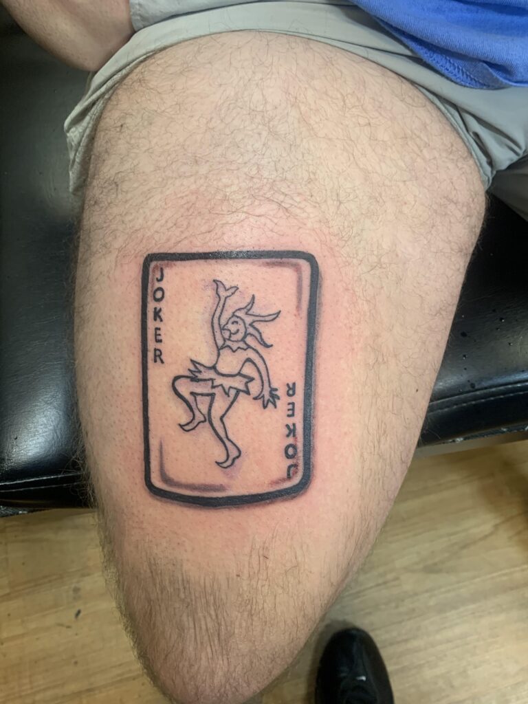 Vivid Joker card thigh tattoo design showcasing the daring nature, rebellious spirit, and the unpredictable character of the Joker card.